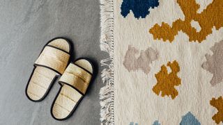 cream rug with colourful blotches next to pair of slippers