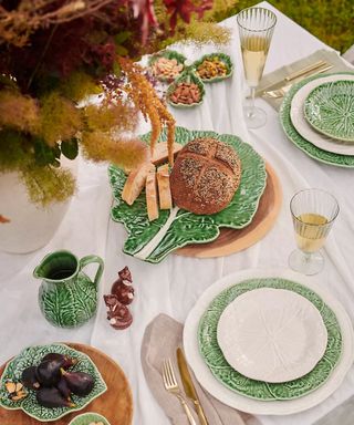 spring table laid outdoors with a white linen tablecloth and cabbageware plates and serveware