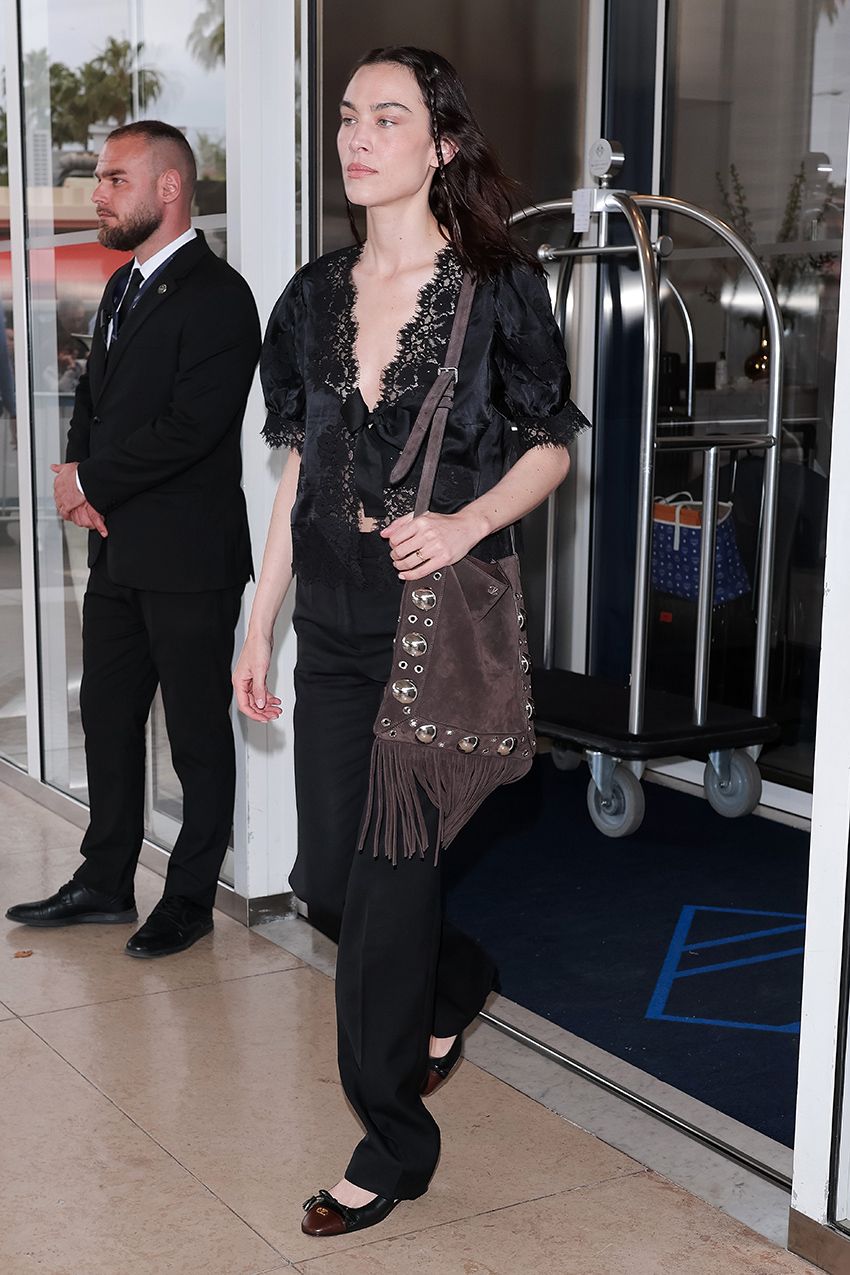 Alexa Chung wearing a black lace top, black pants, and ballet pumps in Cannes
