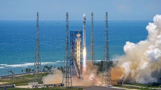 A white Long March 12 rocket lifts off against the backdrop of a rich blue sea.
