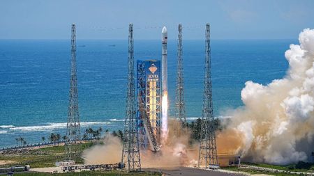 A white Long March 12 rocket lifts off against the backdrop of a rich blue sea.