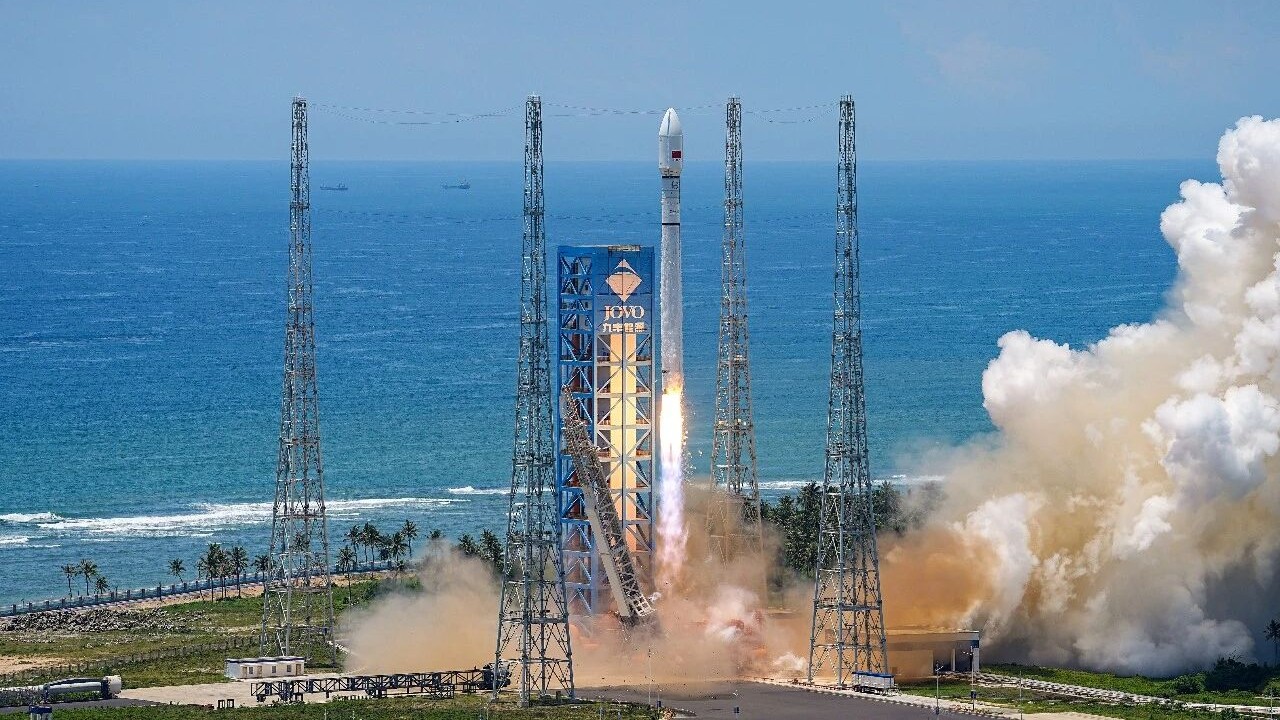 A white Long March 12 rocket lifts off against the backdrop of a rich blue sea.
