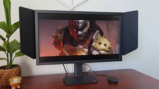 BenQ Zowie XL2586X+ monitor next to plant on desk with DOOM: The Dark Ages cutscene on screen featuring the Doomslayer.
