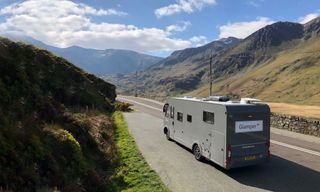 A luxury campervan for hire driving through a scenic landscape