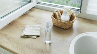 Clean and natural looking cleaning products including a spray bottle and cloth to highlight common kitchen cleaning mistakes of using harsh chemicals
