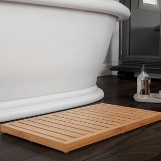 Wooden bath mat next to bath tub