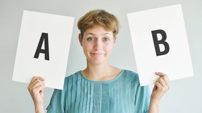 A woman holds up two cards: One says A and one says B.