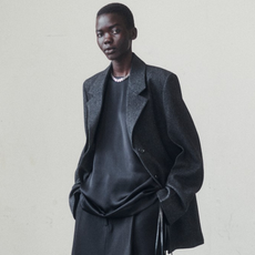 Toteme model wearing black leather jacket, black sweater, and black pants.