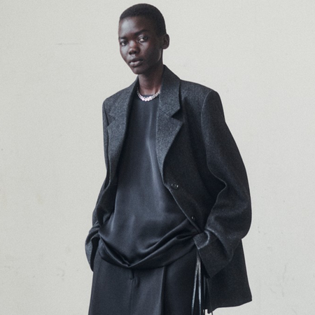 Toteme model wearing black leather jacket, black sweater, and black pants.