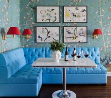 A bright blue breakfast nook with red sconces 