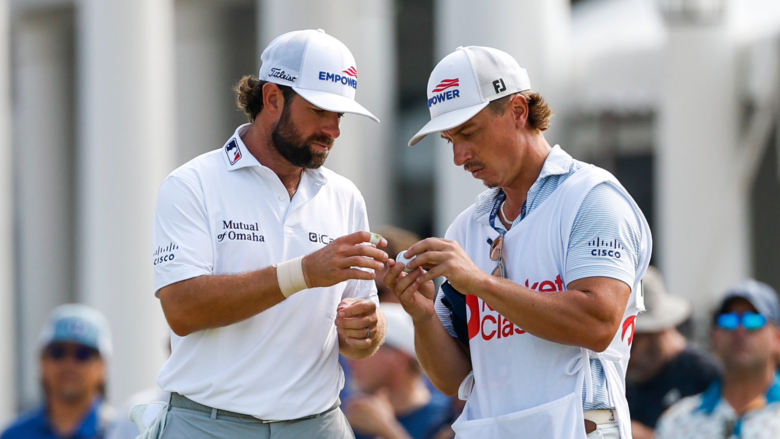 Cameron Young and his caddie look at a golf ball
