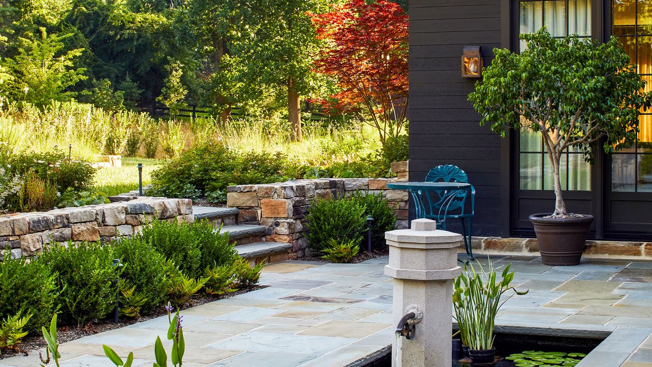 a patio with a water feature and tree in a pot