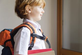 A young blonde boy in his uniform ready for his first day of school