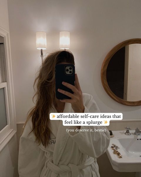 A photo of a woman taking a mirror selfie wearing a bath robe, with the text 'affordable self-care ideas that feel like a splurge'