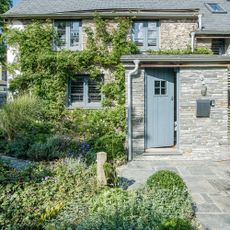 Grey stone house with climbing plants and stone path