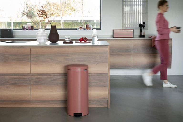 wooden modern kitchen with a modern terracotta pink bin and white walls