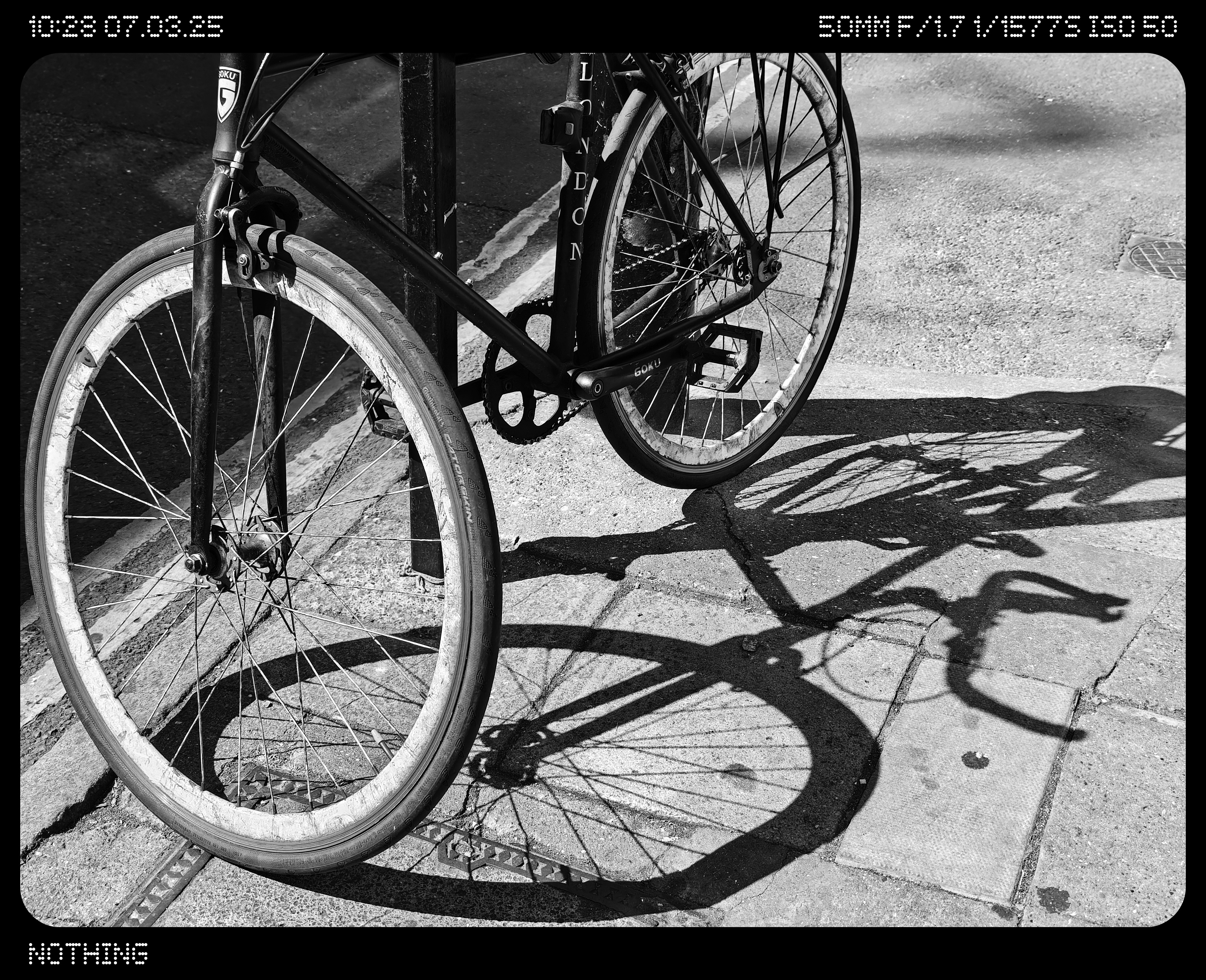 Close-up of a bike tied to a post to casting a shadow