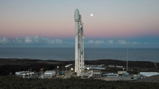 a white rocket sits on a launch pad at sunrise