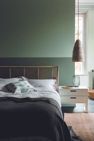 green bedroom with three shades of green painted on the walls, pale blond wood bedside