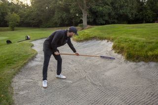 Dan Parker raking a bunker at Edgbaston golf club