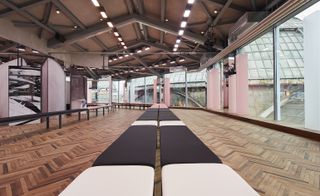View along a line of pink and black padded benches with parquet flooring on either side