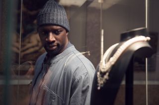 Omar Sy (as Assane Diop) eyes jewelry behind a case in Lupin