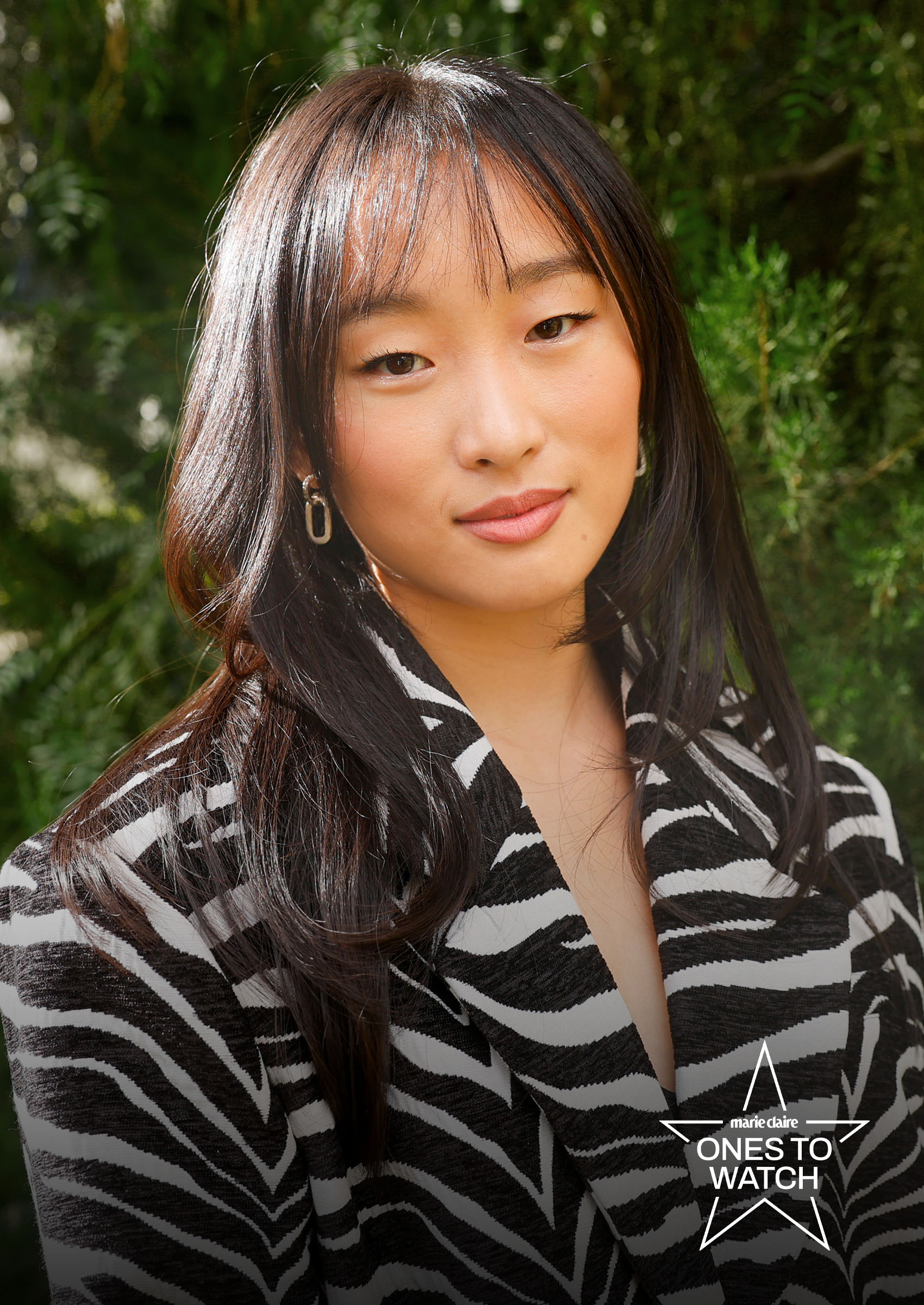 actress ji-young yoo poses in front of trees with a zebra striped jacket on