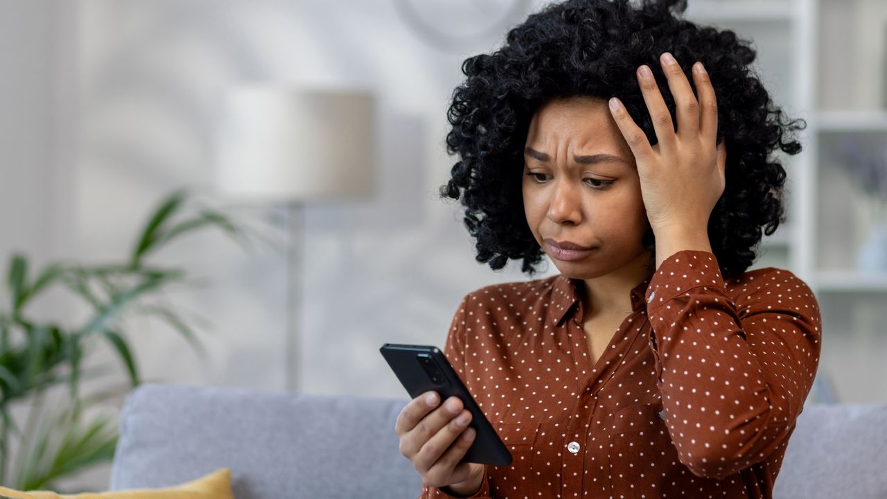 A woman looks concerned as she looks at her phone.