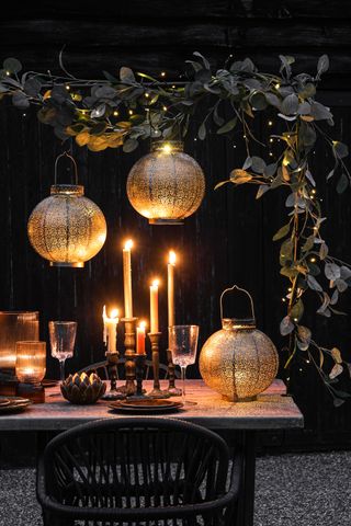 antique brass moroccan solar lanterns over an al fresco dining table with candles and fairy lights