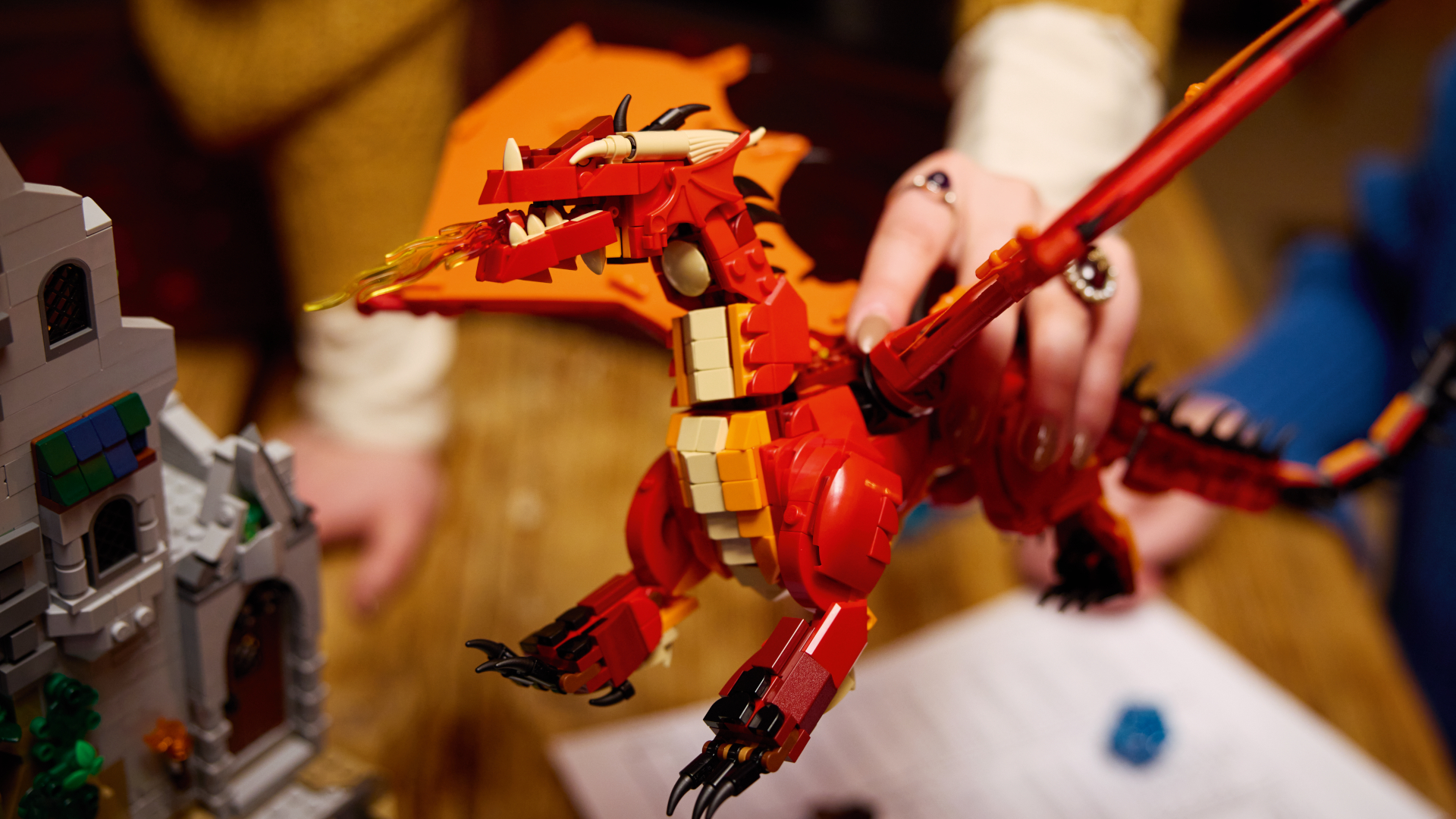 Lego D&D dragon being held above a wooden table and the Lego D&D set