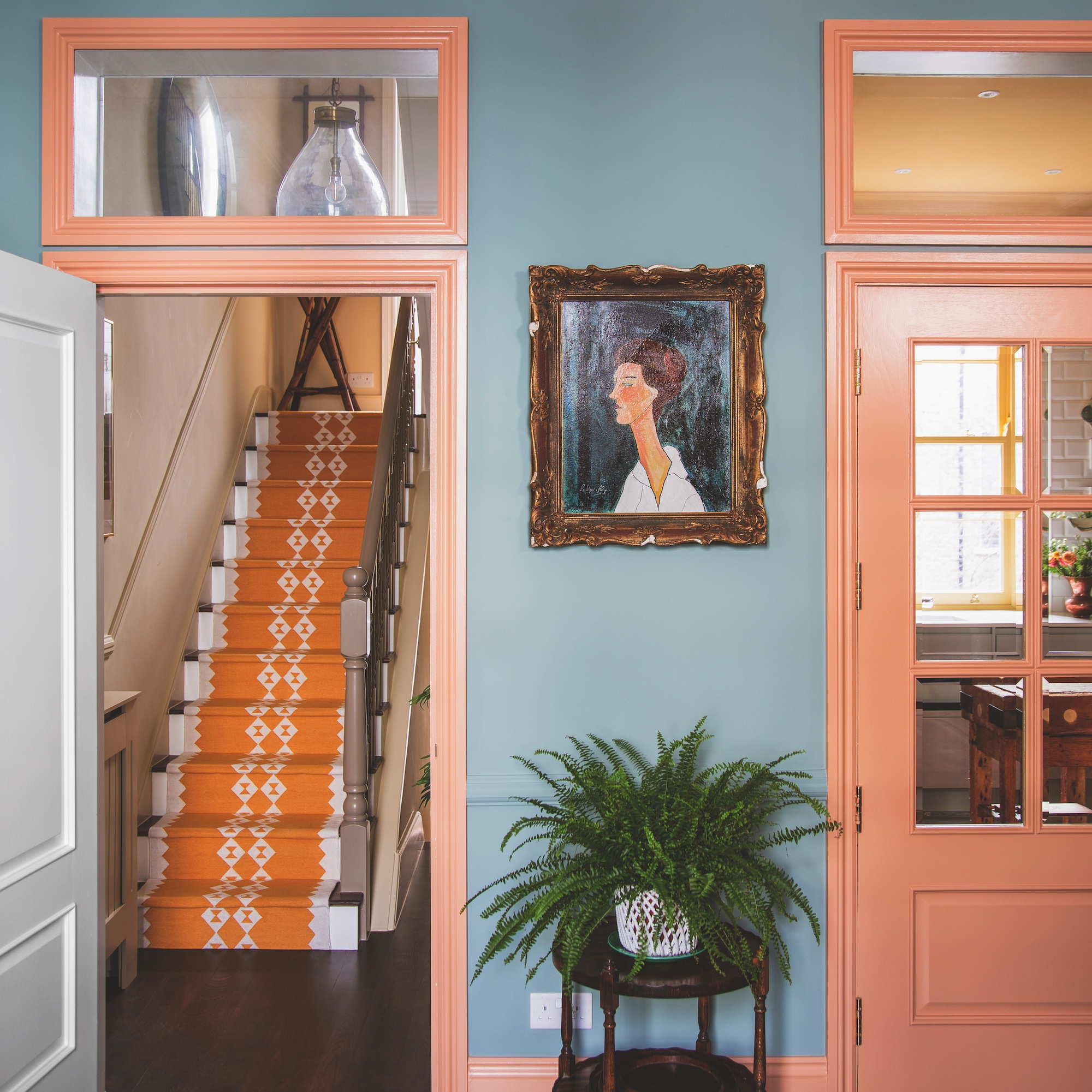 view through to kitchen from room with blue walls and door framed painted in pink