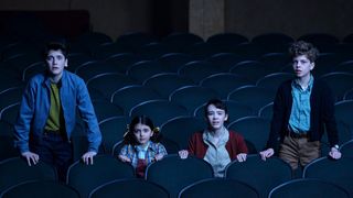 Four children stand in a theater looking scared