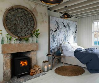 working fireplace in bedroom with large blue and white painting on wall above bed