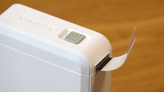 Niimbot D110 review; a small white box printer on a wooden table with colourful stickers