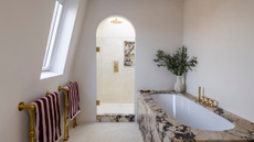 a bathroom with a marble tub and an arched shower with marble trims