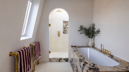 a bathroom with a marble tub and an arched shower with marble trims