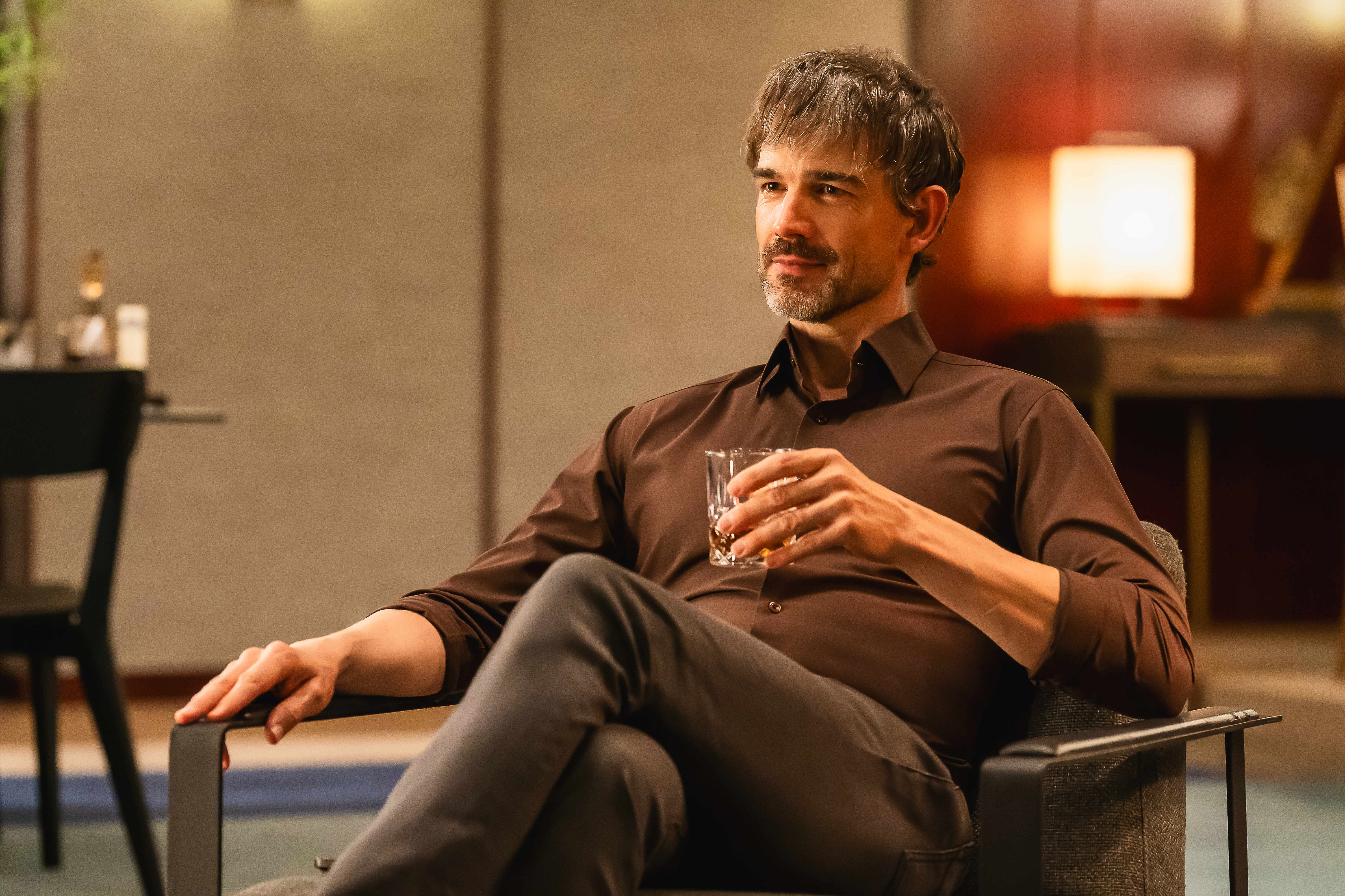 Christopher Gorham holds a drink and sits in a chair in &#039;Tempest.&#039;