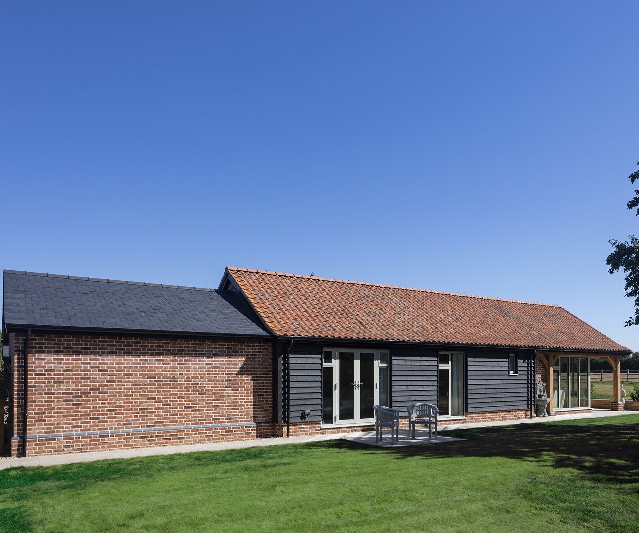 A pitched roof barn-style home clad in red brick and timber