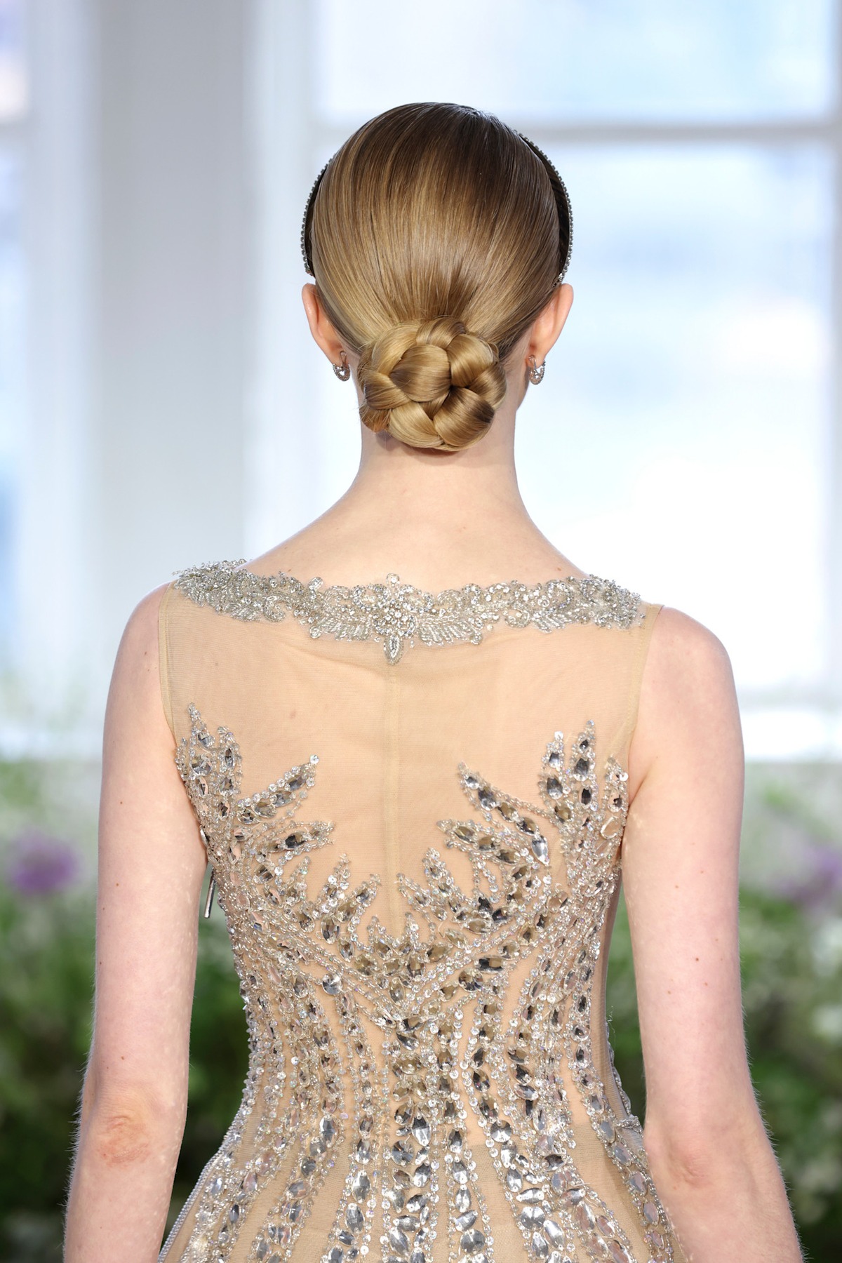A model showing off a braided bun wedding hairstyle.