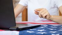 Girl working on laptop on table with American flag