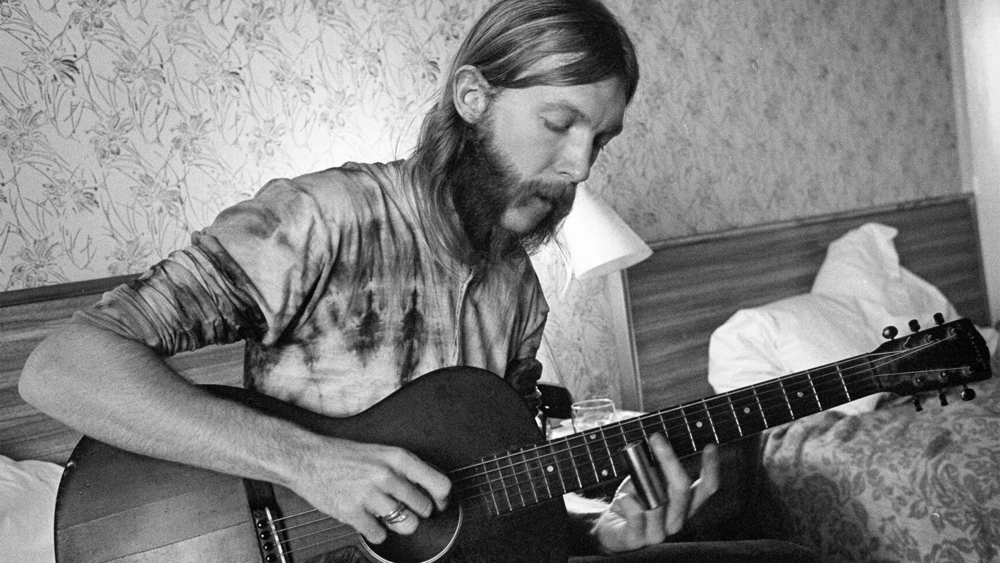 Guitarist Duane Allman uses a steel slide on an acoustic guitar in his hotel room before the Allman Brothers' performance at the Sitar on October 17, 1970 in Spartanburg, South Carolina.
