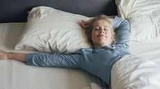 A woman wakes up and stretches in bed after enjoying a good night's sleep