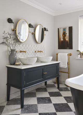 White tiled bathroom with blue vanity unit and brass fixtures by BC Designs