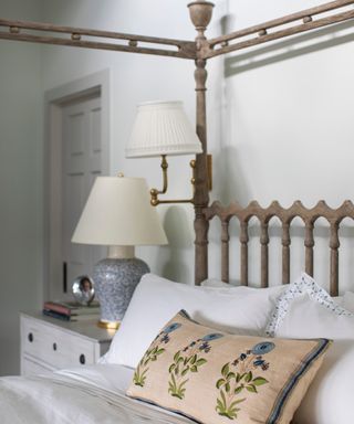 neutral bedroom with wooden four poster, white bedlinen, floral pillow