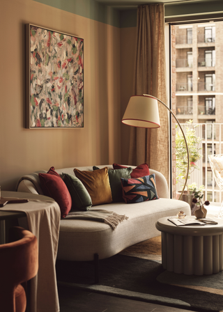 Sofa by big window in a flat with an arched lamp