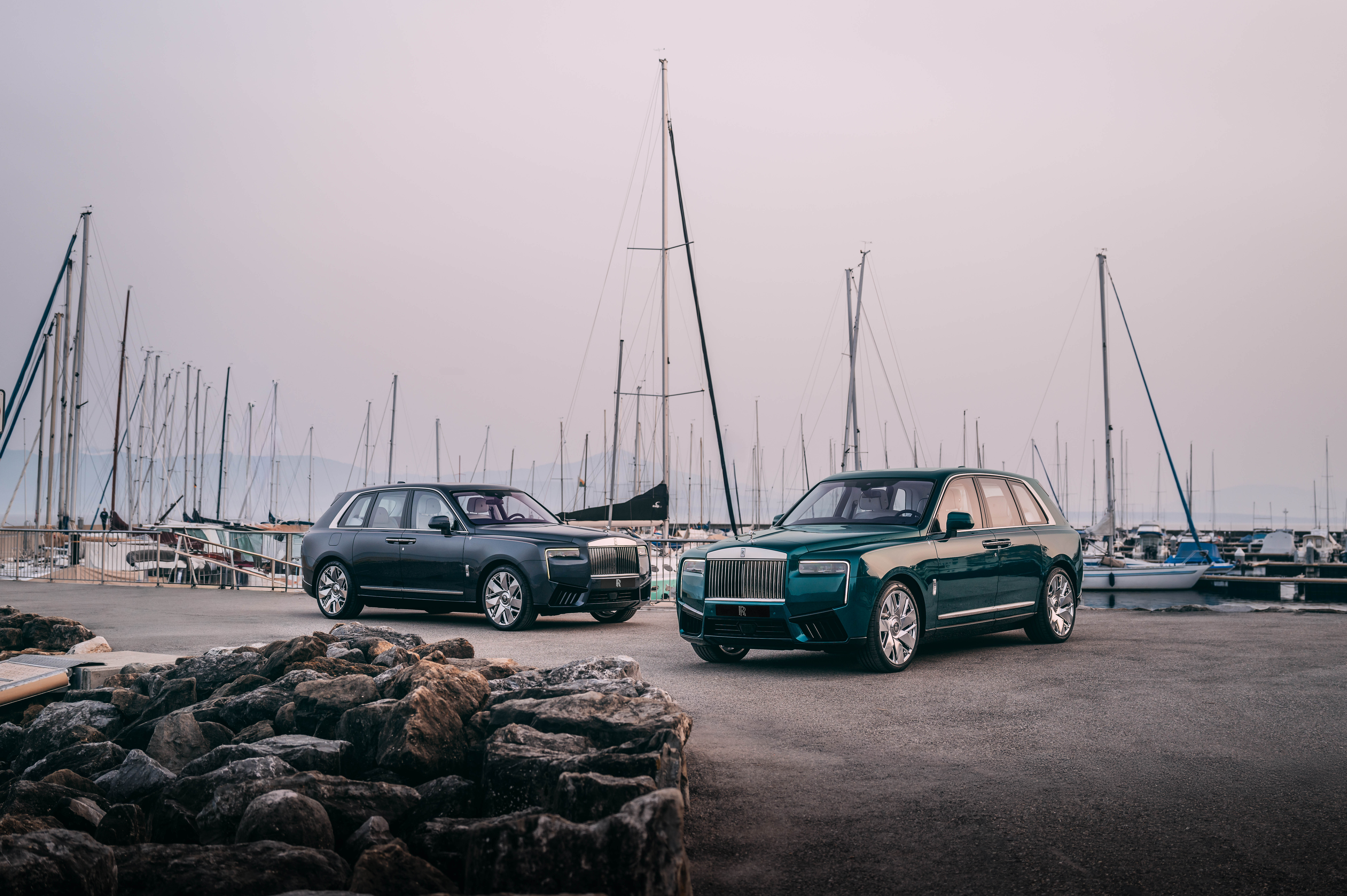 Two of the bespoke Cullinanas, East and West, parked in front of a marina with masts in the background