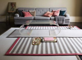 A living room floor with neutral and stripy layered rugs