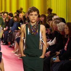 a model on the Paris Spring 2026 runway wearing a pocketed apron by Miu Miu