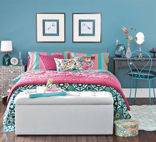 Turquoise bedroom with patterned bedding and neutral ottoman