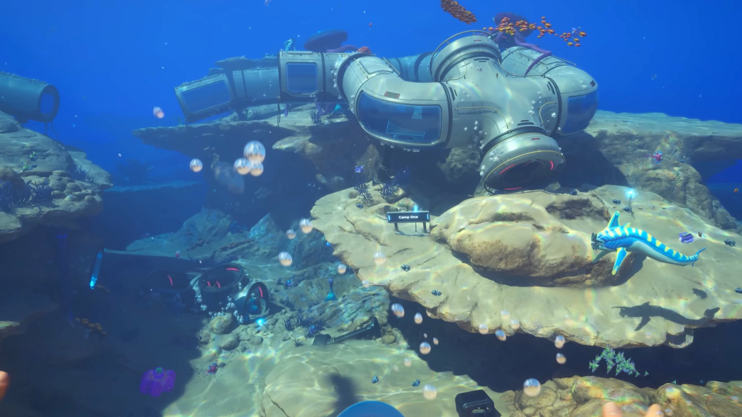 Subnautica 2 inventory size: A ruined underwater habitat with a small blue fish swimming past.